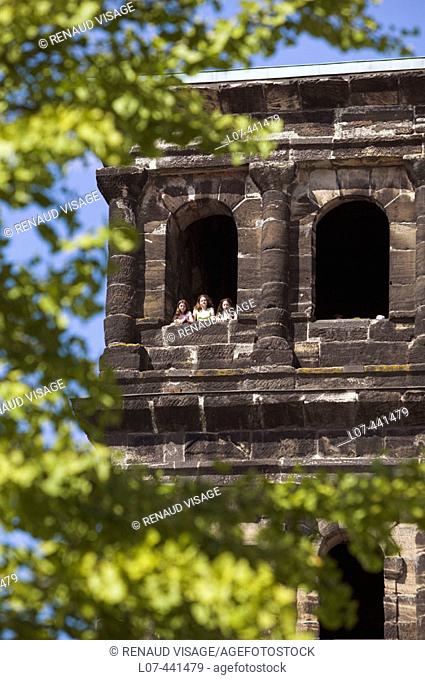Three girls looking out from a window of the Porta Nigra. Trier. Moselle River Valley. Germany