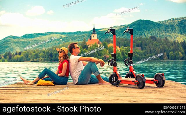 Young couple using electric scooter as modern ecological mean of transport while exploring green country Slovenia at vacations
