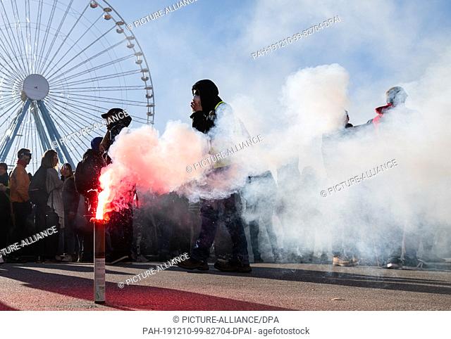 10 December 2019, France (France), Lyon: Pyrotechnics burns during a demonstration in the context of strikes and protests against the pension reform in France...