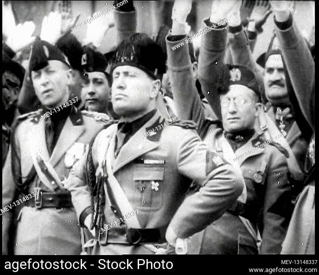 Benito Mussolini, the Italian Leader, Making a Speech and Standing With His Hands on His Hips in Front of a Crowd of Uniformed Male Italian Fascist Officials...