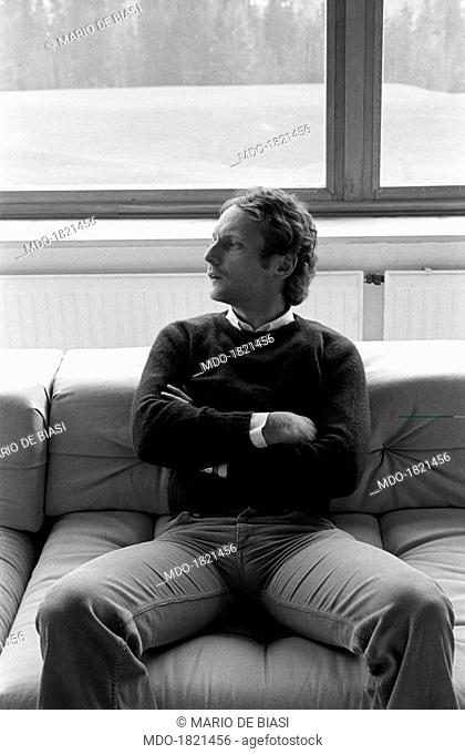 Austrian racing car driver and sport manager Niki Lauda (Andreas Nikolaus Lauda) sitting on the sofa with folded arms in his house in Salzburg countryside