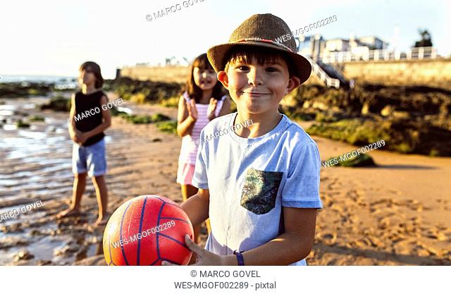 Portrait of boy with a ball on the beach at sunset