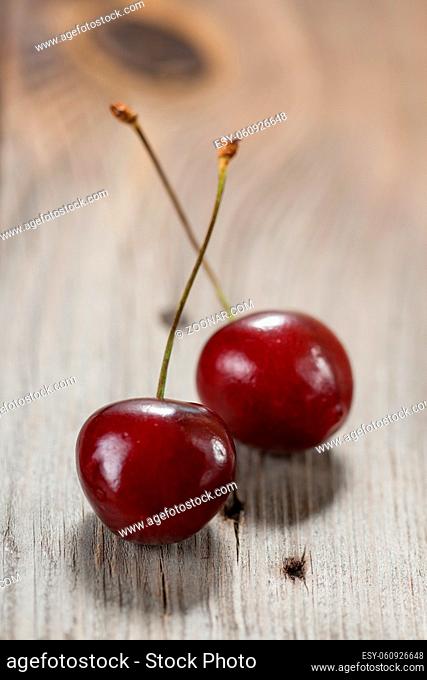 Two sweet cherries berries on a wooden background