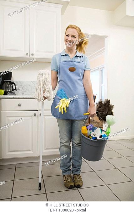 Woman holding mop and cleaning supplies