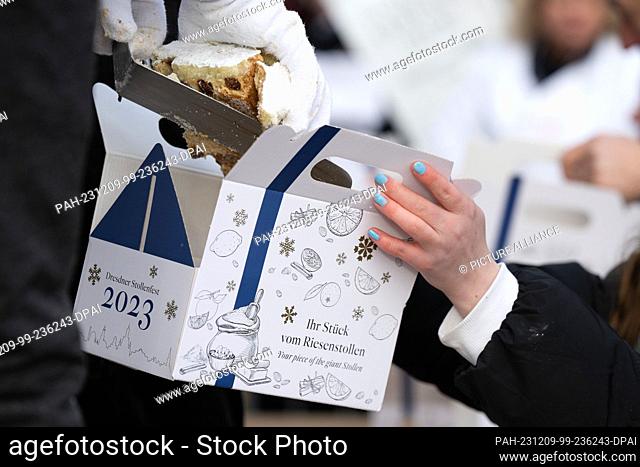09 December 2023, Saxony, Dresden: A piece of the giant stollen is packed in a cardboard box at the Dresden Stollen Festival