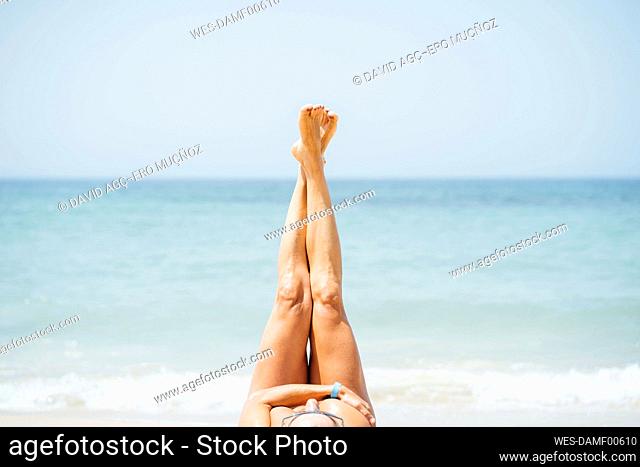 Woman with feet up lying on beach during sunny day