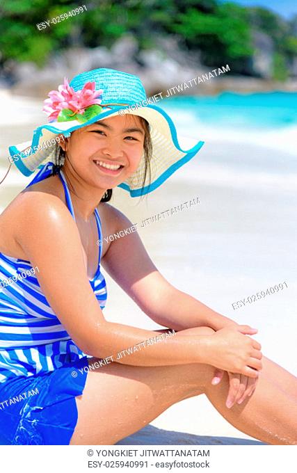 Girl in a blue swimwear sitting a happy on the beach with the sea as background during summer at Koh Miang Island, Mu Ko Similan National Park