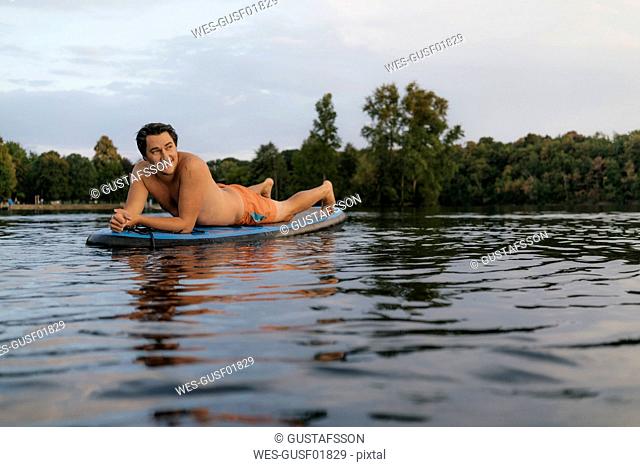 Man lying on SUP board on a lake