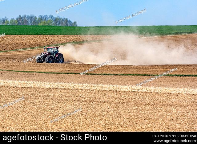 09 April 2020, Bavaria, Kleinpinning: A farmer kicks up dust with his tractor while working a field. Photo: Armin Weigel/dpa