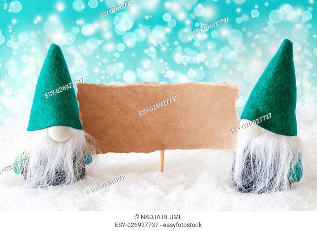 Christmas Greeting Card With Two Turqoise Gnomes. Sparkling Bokeh Background With Snow. Copy Space For Advertisement