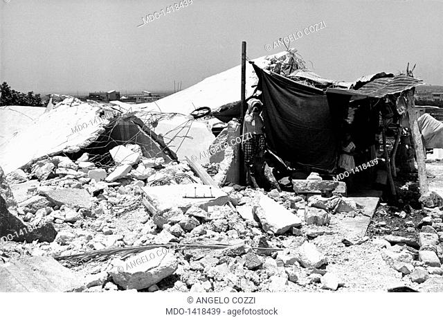 A tent among the ruins of a collapsed house. A woman with her children under a tent among the remains of a collapsed house after the Israeli bombardment of the...