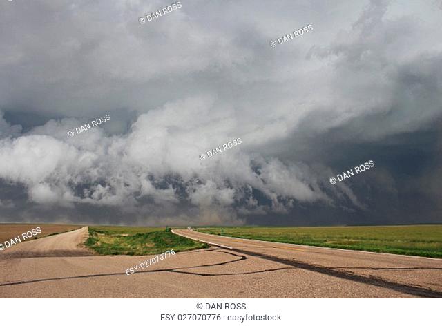 Powerful thunderstorm winds gust outward underneath a low hanging shelf cloud, stirring up dust