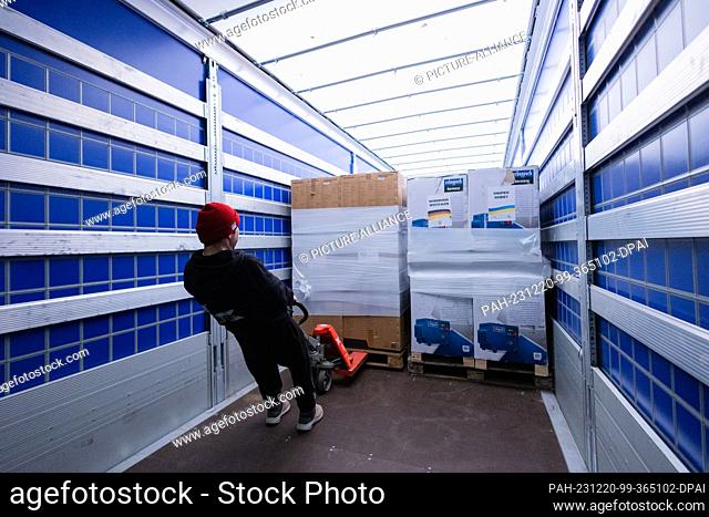 20 December 2023, North Rhine-Westphalia, Cologne: Electricity generators are loaded onto a truck at the ""Blue-Yellow Cross"" donation warehouse