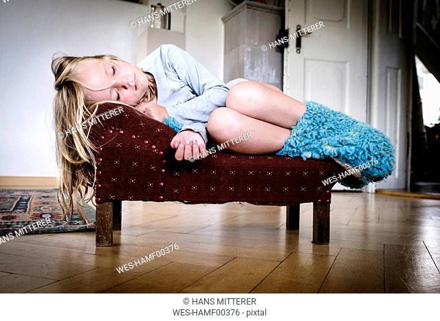 Little girl sleeping on a tiny vintage sofa