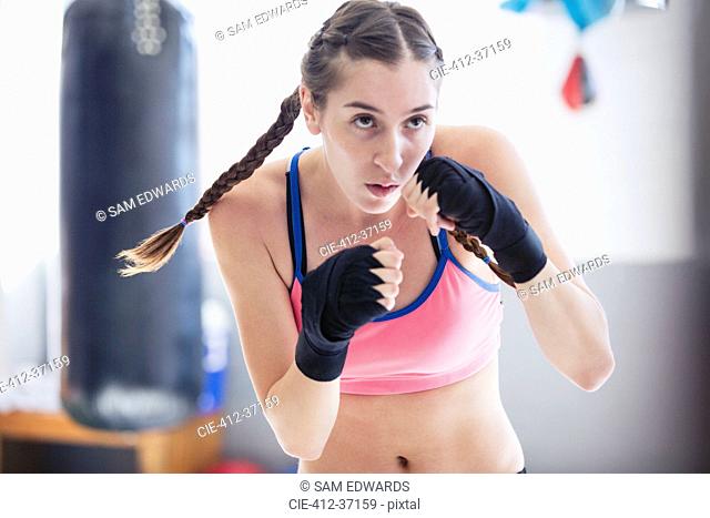 Determined, tough young female boxer shadowboxing in gym