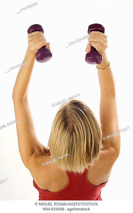 Young woman, blonde, exercising with weights in the gym to get fit