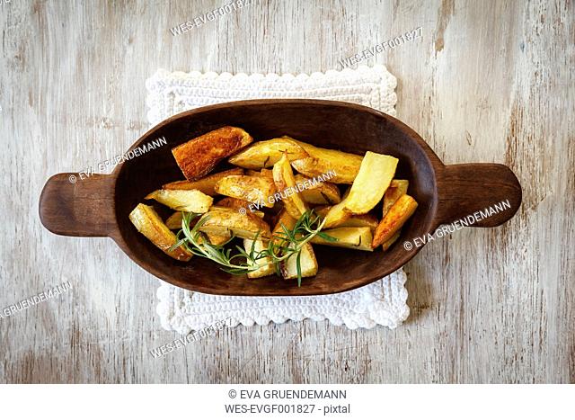 Wooden bowl of potato wedges with rosemary