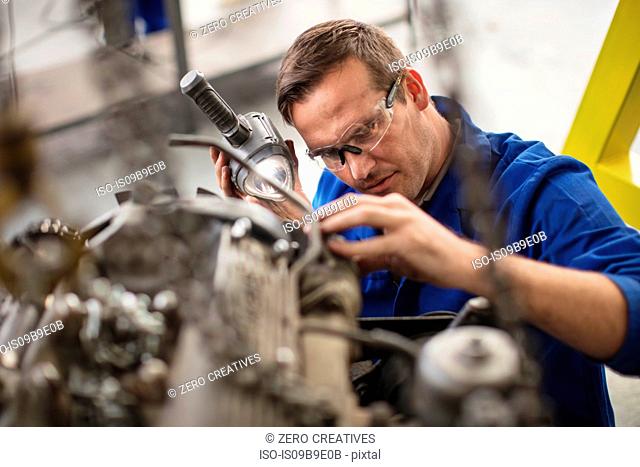 Car mechanic inspecting car part in repair garage