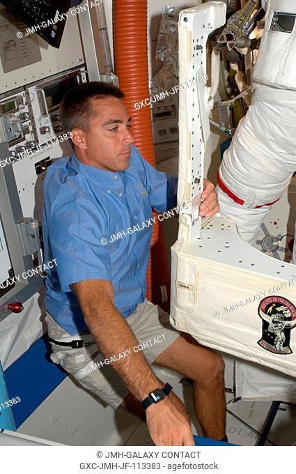 Astronaut Christopher Cassidy, STS-127 mission specialist, assists astronaut Dave Wolf (partially pictured), mission specialist