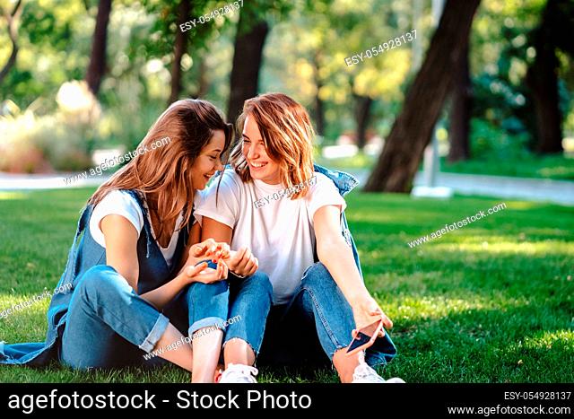 Candid friends seated at the park talking to each other. Girlfriends speaking in conversation outdoors