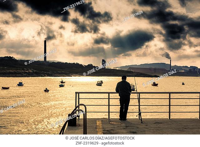 A man contemplates an aluminium plant from the port of San Ciprian, Lugo, Galicia, Spain