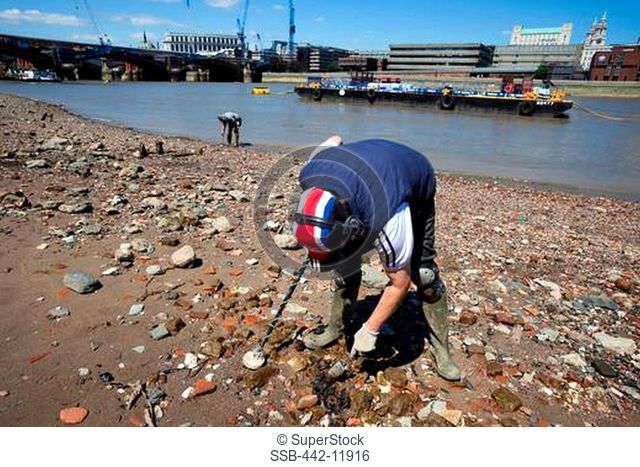 UK, England, London, Southwark, Man metal detecting by River Thames