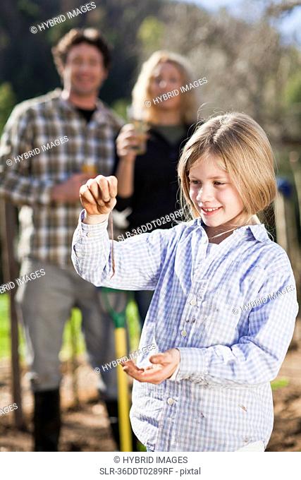 Girl holding earthworm in garden