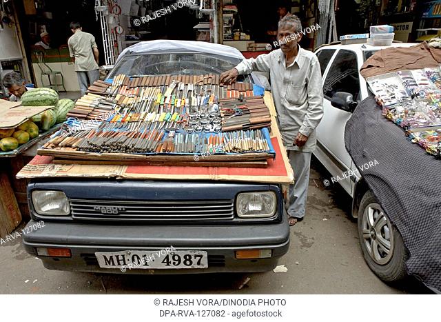 A hawker finds an ingenious way to display his ware on the bonnet of a car ;  Mumbai Bombay ; Maharashtra ; India