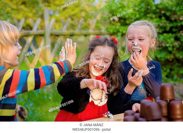 Three children making eating contest with chocolate marshmallows