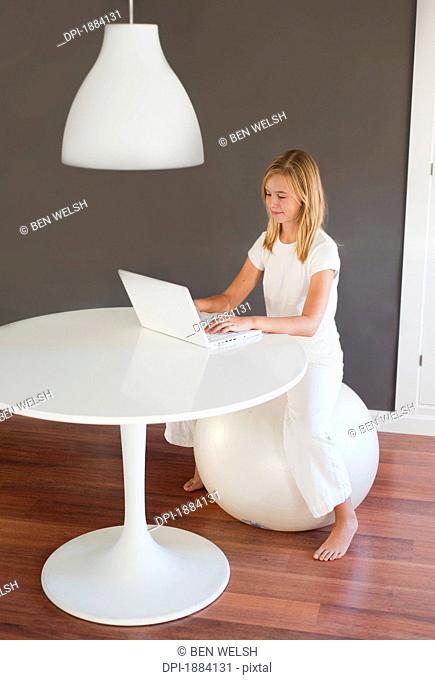 a girl wearing white using a white laptop computer in a room furnished in white, benalamadena costa, malaga, andalusia, spain