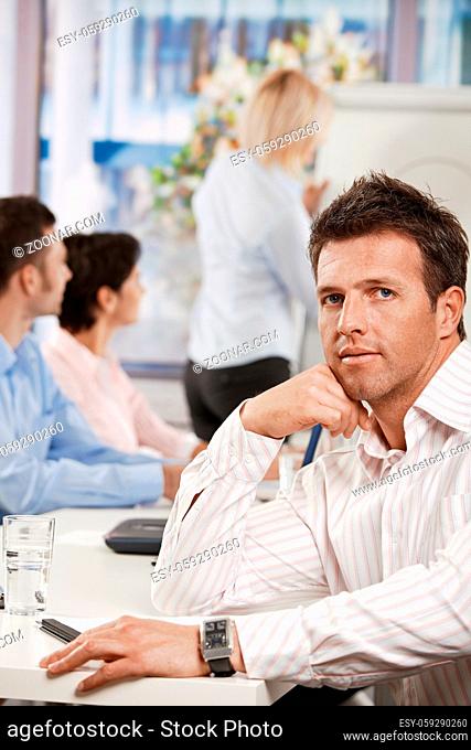 Businessman sitting at table in meeting room at office, looking at camera