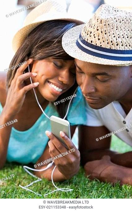Happy young couple listening to music on the grass