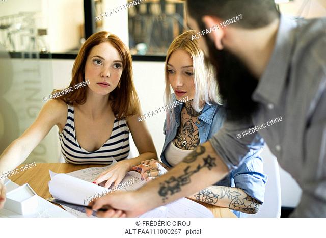 Colleagues discussing blueprints together in casual office