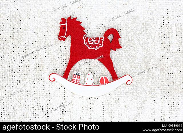 scandy style rocking horse Christmas ornament across a white jute background with copy space for text