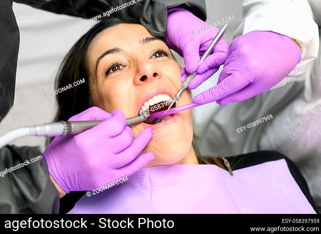 Young woman visit dentistry clinic for professional teeth treatment. Woman dentist bend over patient. Doctor holding instrument tool for oral examination
