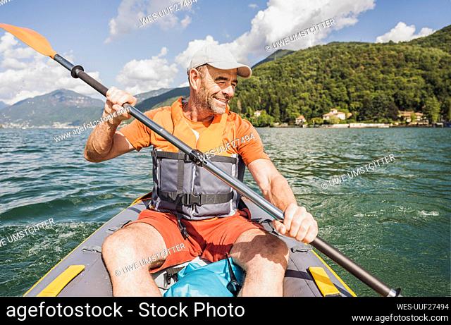 Smiling man kayaking at lake on sunny day