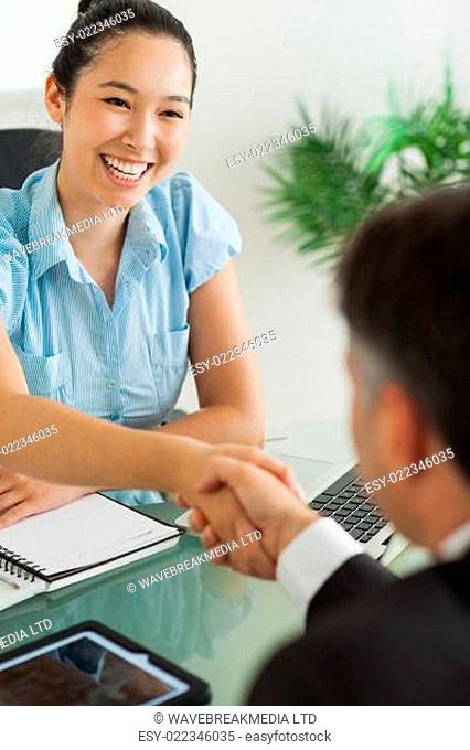 Happy businesswoman shaking man's hand in her office