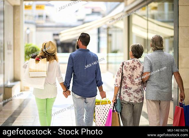 group or family walking together in a mall doing shopping and holding shopping bags - adults and seniors looking at the shops or stores