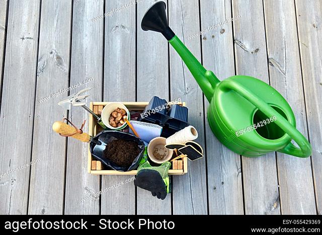 box with garden tools and watering can in summer