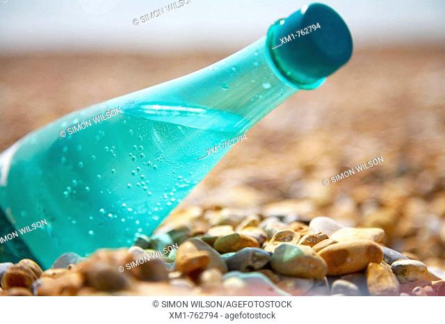 Green plastic bottle of mineral water on a beach