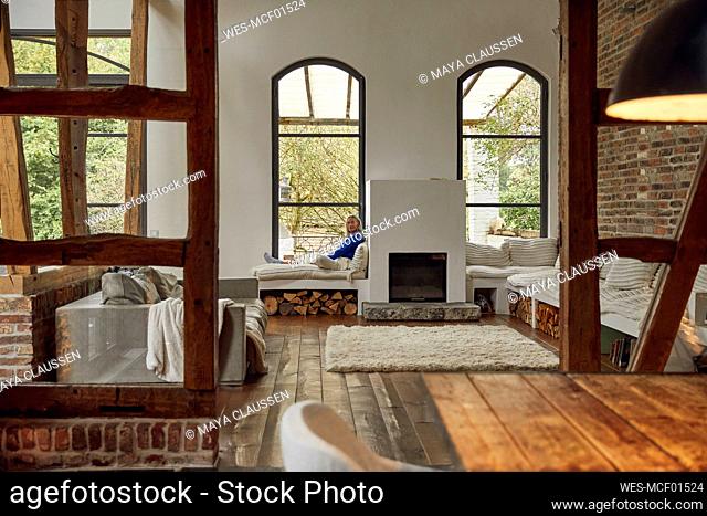 Mature woman sitting on window seat at home