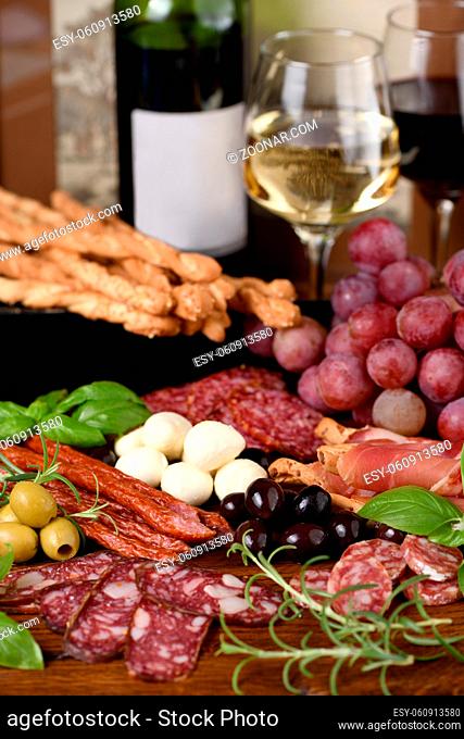 Antipasto. Dish with sausage, dried ham, salami, crispy grissini with grapes. A meat appetizer is a great idea for wine