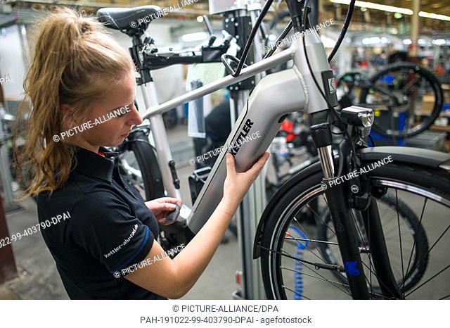 22 October 2019, Saarland, Hanweiler: An employee sticks a Kettler name on a bicycle. Kettler Alu-Rad GmbH manufactures its bicycles in Hanweiler, Saarland