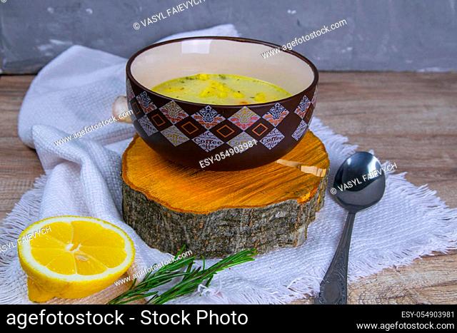 Potato cream soup with mushrooms, carrots and cheese. Top view. Soup in a brown plate, stands on a wooden stand, next to a hour, spoon, spices and lemon