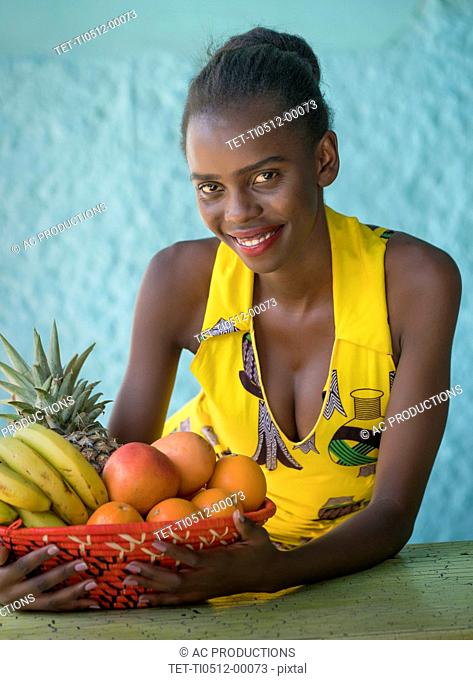 Smiling young woman holding fruit bowl