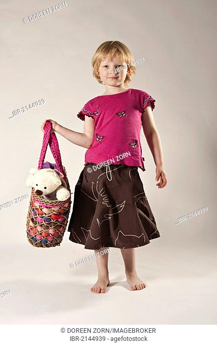 Girls, 5, carrying a teddy bear in a bag