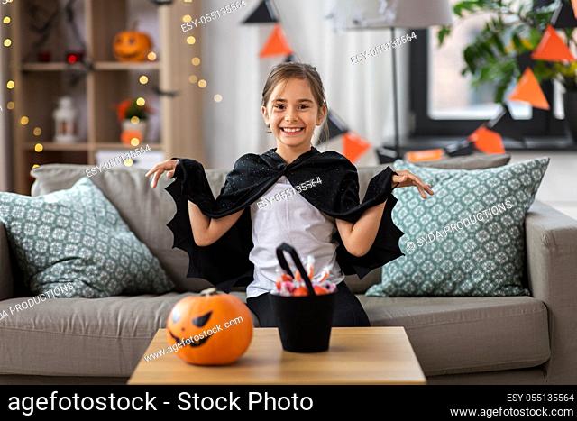 girl in halloween costume with bat cape at home