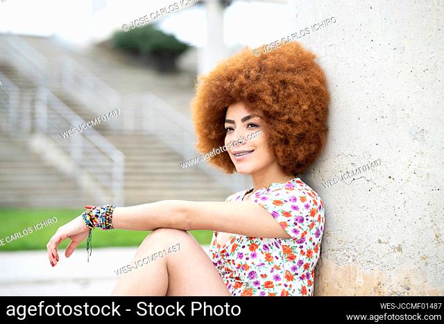 Young woman day dreaming while leaning on wall at park