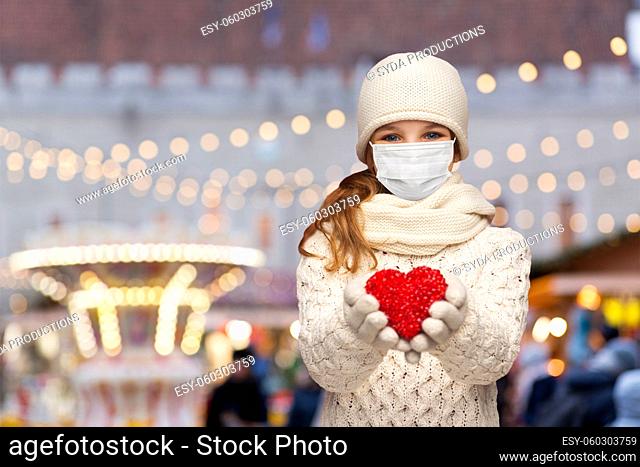 girl in mask with heart over christmas market