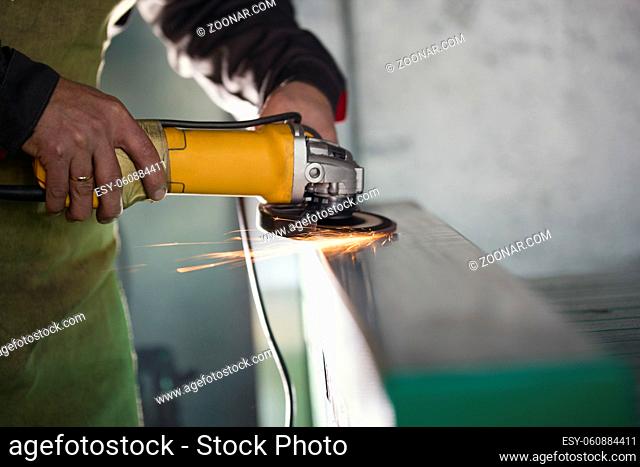 Manual labour - worker grinding the steel mechanism on the plant, close up